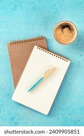 Notebook mockup with a pen and a cup of coffee, top shot on a turquoise background