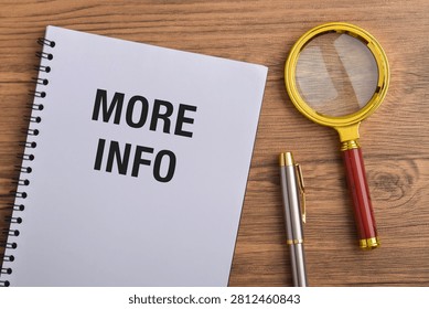 Notebook with More Info text, magnifying glass, and pen on wooden desk. Concept of information search, research, knowledge gathering, inquiry, documentation, and data collection.