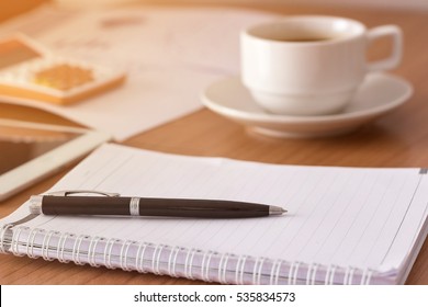 notebook or notepad blank with a pen on top and a coffee cup put on right side, It has been on office desk for work, business concept.