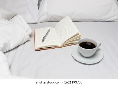 Notebook on Bed with coffee and ready to relax and do journal writing in peace and tranquil bed with white sheets - Shutterstock ID 1621193785