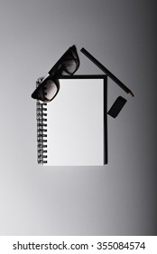 Notebook on a gray background with glasses, black pencil and rubber