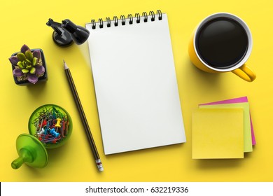 Notebook on office table with a cup of coffee, plant, stationery and office supplies. Blank notepad paper for input copy or text. Top view desk, flat lay yellow color background concept.