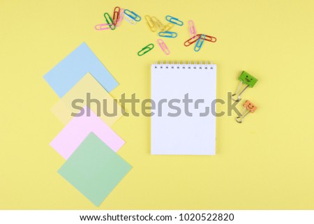 Notebook on office table with a cup of coffee, plant, stationery and office supplies. Blank notepad paper for input copy or text. Top view desk, flat lay yellow color background concept.
