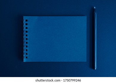 Notebook On A Spring And A Pen On A Black Background. Space For Text. Toned Classic Blue Color