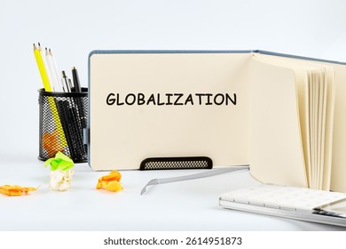 A notebook opened to the word globalization, surrounded by pencils and colorful paper scraps, illustrating a focus on global themes in a clean workspace.