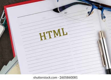 A notebook page displays the term HTML, while reading glasses and a pen rest nearby on a study desk cluttered with books and notes.