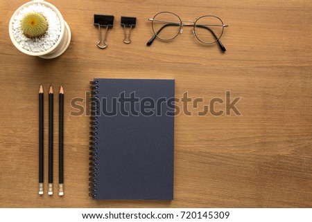 notebook papers, pencils, clips, tree and glasses on wood office desk with copy space  