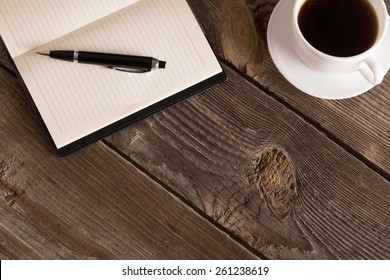 Notebook With Pen And Coffee  On Old  Wooden Table