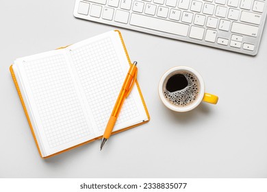Notebook with pen, cup of coffee and computer keyboard on white background