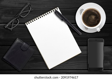 Notebook, Pen And Cup Of Coffee, Glasses And Purse On A Wooden Dark Table, Top View