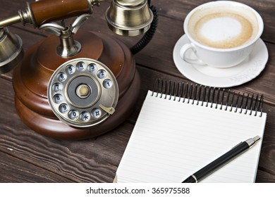 Notebook with a pen on the table next to coffee and phone