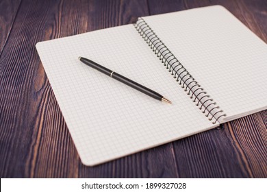 A Notebook With Pen On Wooden Table