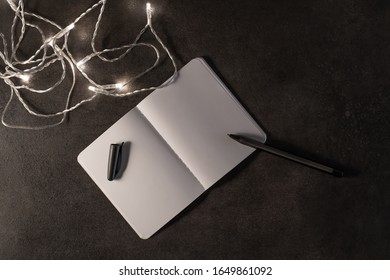 A notebook, a pen and small lights