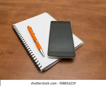 Notebook and pen with smartphone lying on the desk