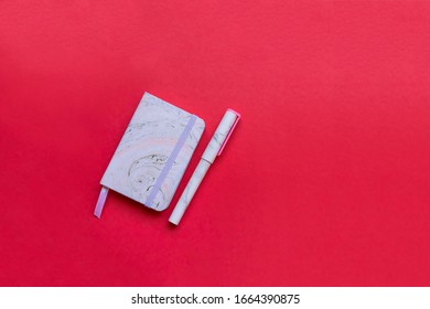 Notebook and pen with trendy marble pattern flat lay on pink background. Picture with place for text