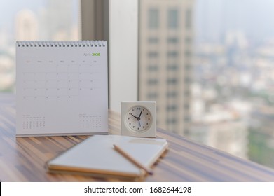 
Notebook with pencil diary clock on table with April 2020 calendar at office work place with blurred background. Planning scheduling agenda Event organizer writing detail. Calendar concept.