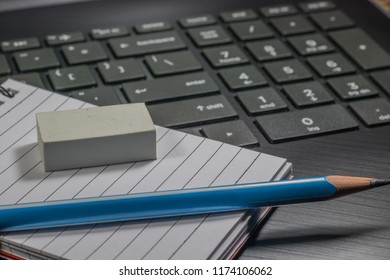 A notebook, pencil and eraser on a laptop depicting technology in business, finance and workplace concept