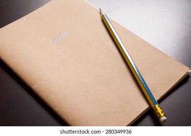 Notebook and pencil on wooden table