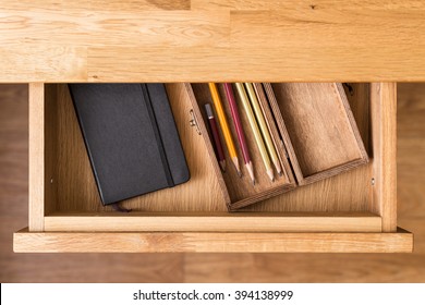 Notebook and pencils in open desk drawer top view image. Drawing background