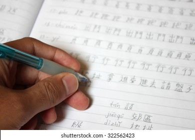 A notebook with a person handwriting Chinese characters - Study and learn Mandarin