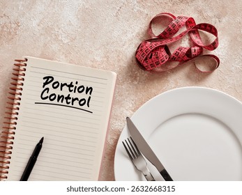 Notebook with portion control written, measuring tape and cutlery suggesting a healthy lifestyle and weight loss diet