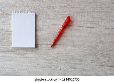 Notebook and red pen on the wooden table. Top view, copy space. Business still life.