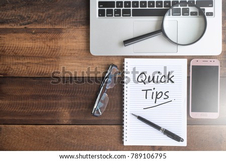 Notebook, smartphone, magnifying glass, spectacles and QUICK TIPS word. quick tips flat lay concept