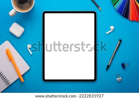 Notebook and Tablet Computer on Blue Desk or background laying flat on Creative workplace as mockup or Template with empty or blank page or screen
