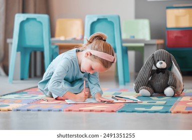 Notebook, teddy bear and young child writing in psychology office for social development. Growth, plush toy and girl kid patient drawing on floor at healthcare clinic for cognitive behavioral therapy - Powered by Shutterstock