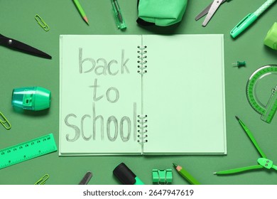 Notebook with text BACK TO SCHOOL and different school stationery on green background, closeup