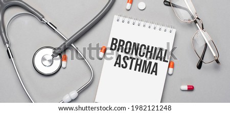 In the notebook is the text bronchial asthma, next to a stethoscope, pills and glasses.