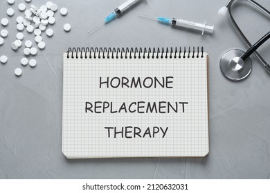 Notebook With Text Hormone Replacement Therapy, Pills, Stethoscope And Syringes On Grey Background, Flat Lay