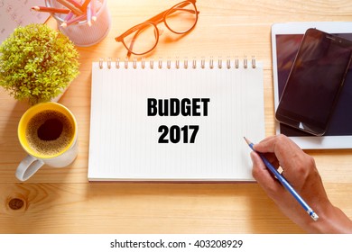 Notebook with text inside BUDGET 2017  on table with coffee.