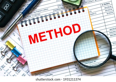 The notebook with the text Method lies on the financial tables with a calculator a magnifying glass a compass and paper clips. Financial concept - Shutterstock ID 1931211374