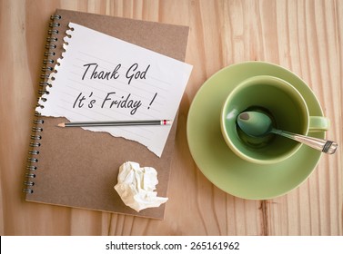 Notebook with text "Thank God It's Friday!" with empty coffee cup