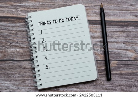 Notebook with things to do today list on wooden desk with pen.