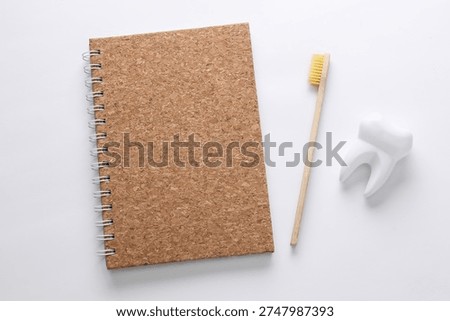 Notebook, tooth model and toothbrush on a white background. Dental Hygen concept