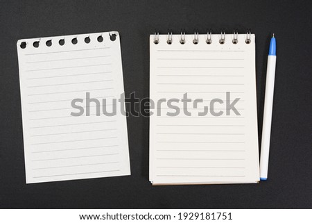 notebook with white sheets in a line on a black background, close up
