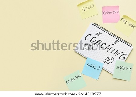 Notebook with word COACHING and sticky notes on beige background