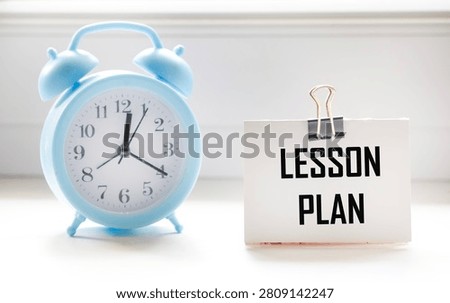 A notebook with the word Lesson Plan written on a white background with a clock