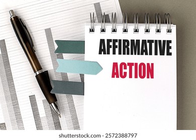 Notebook with the words Affirmative Action placed on financial documents with a pen and sticky notes 