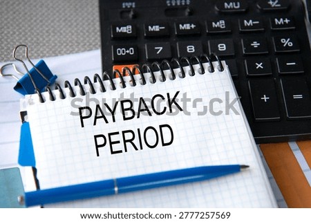 Notebook with the words PAYBACK PERIOD in the notebook on the background of a black calculator