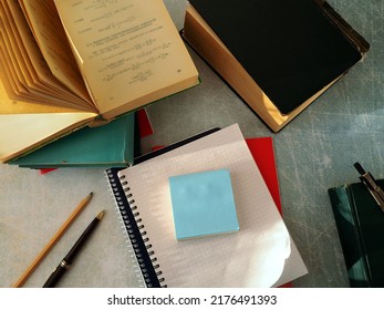 Notebooks and paper for notes are stacked. Books, pen, pencil, and compass are arranged around them in working order. The concept of scientific work, training, education.