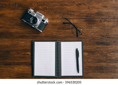 Notepad, camera and glasses. Top view, flat lay