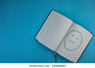 Notepad With Confused Facial Expression Placed On Blue Background.