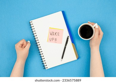 Notepad and cup of coffee in woman's hands, wake up concept.