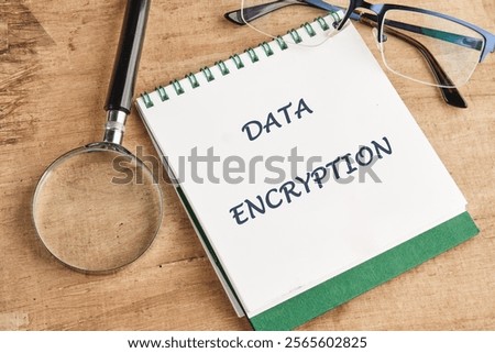 Notepad displaying the phrase data encryption alongside a magnifying glass and glasses on a wooden surface emphasizes the importance of encryption in technology and cybersecurity.