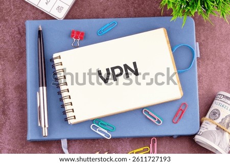 A notepad featuring the abbreviation VPN is set on a desk surrounded by colorful stationery clips, a pen, and a stack of cash in a productive workspace.