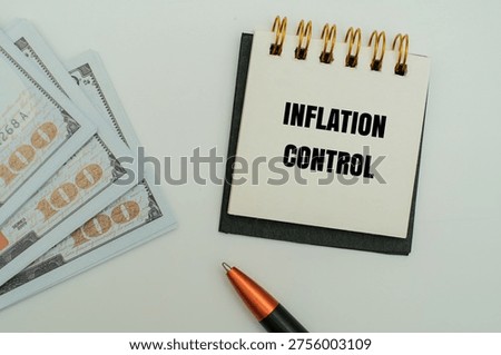 A notepad with INFLATION CONTROL text, alongside US hundred-dollar bills and a pen. A concept for financial planning, monetary policy and economic stability