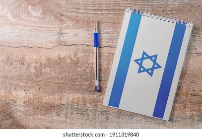 Notepad with Israel flag, pen on wooden background, study concept